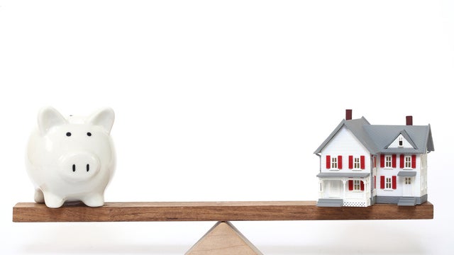 Model house and piggy bank on seesaw - Concept of Investment in real estate 