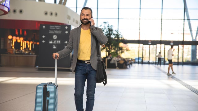 Man traveler walking through airport and talking on phone 