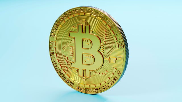 Three dimensional render of Bitcoin standing against blue background 