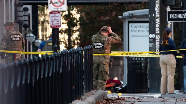 National Guard members stand together behind yellow tape after two guard members were shot near the White House in Washington, D.C., Nov. 26, 2025. 
