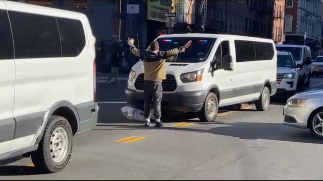 Individual stands in front of unmarked police van 