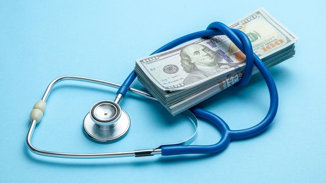 Stack of cash dollars and stethoscope on blue background. The concept of medical strechevka or expensive medicine, doctors salary 