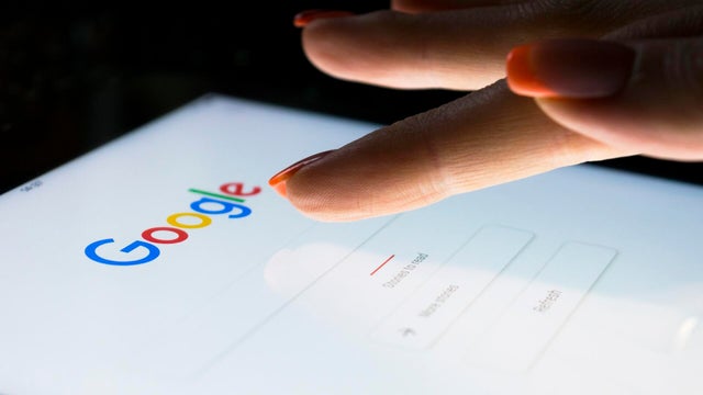 A woman's hand is touching screen on tablet computer iPad Pro at night for searching on Google search engine. Google is the most popular Internet search engine in the world. 