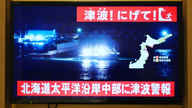 A tsunami warning is issued as live footage shows a boat leaving a port on a television in Sapporo, in Japan's northern Hokkaido prefecture, Dec. 8, 2025. 