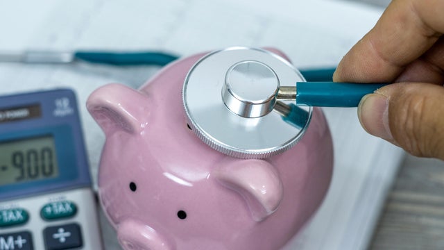 Financial health check on debt or loan concept, saving pink piggy bank with stethoscope. 