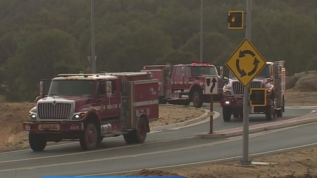 Three fire trucks driving on the road. 