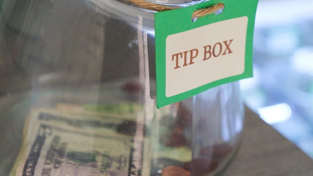 Glass tip jar at checkout counter with a few dollars in it. New York USA 
