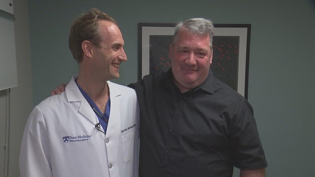 Burkhardt and Monaghan smile for a photo in a doctor's office 