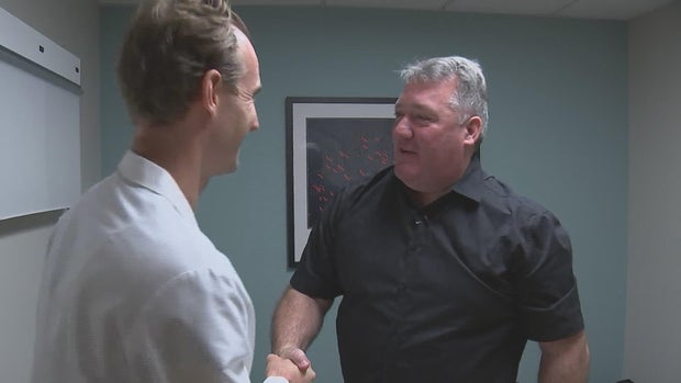 Monaghan and Burkhardt shake hands in a doctor's office