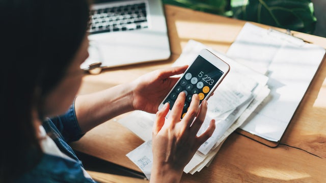 Woman accountant use calculator and computer with holding pen on 