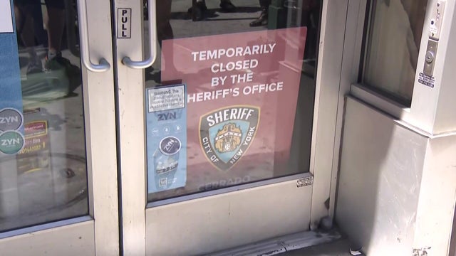 A sign in a shop window reading "temporarily closed by the sheriff's office." 