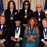 Back row from left to right, Paul Stanley, Gene Simmons and Peter Criss of Kiss and, front row from left to right, Sylvester Stallone, George Strait, Gloria Gaynor and Michael Crawford pose for the class photo at the Kennedy Center Honors medallion reception at the State Department on Dec. 6, 2025 in Washington. 