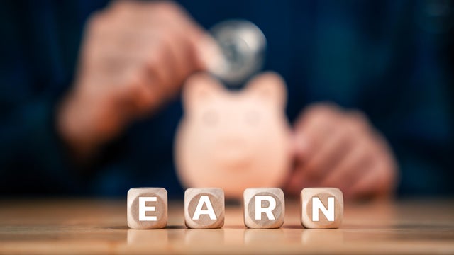 Saving Money, Piggy Bank and Investment Planning with Close-Up of Hand Putting Coins into Piggy Bank 