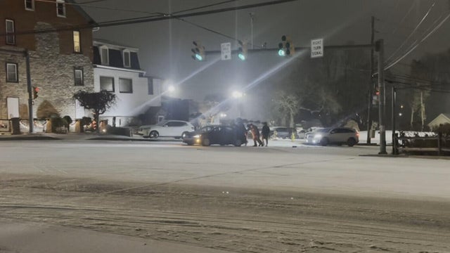 People push a car on a snowy road in the Lehigh Valley 