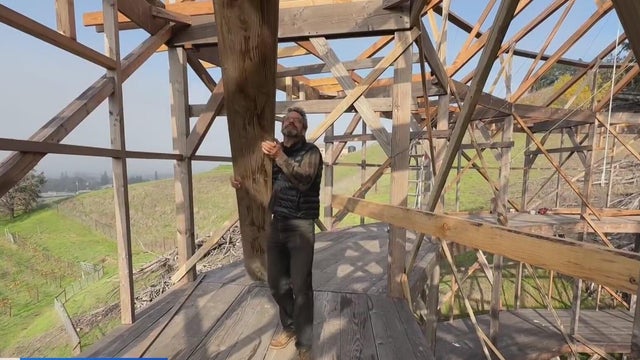 A man carrying cut lumber inside of a round structure 