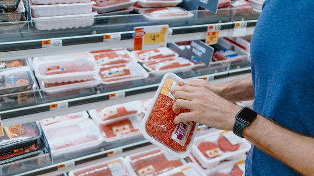 Man Checks Price of Ground Beef at Supermarket 