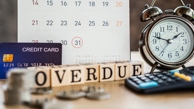 overdue bills concept with deadline calendar remind note,coins,credit card,calculator on table 