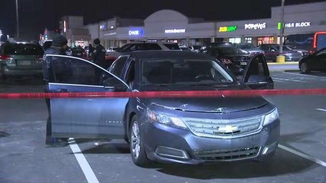 Red police tape is seen near a car with an open door in the parking lot of a shopping center on the 2900 block of Island Avenue 