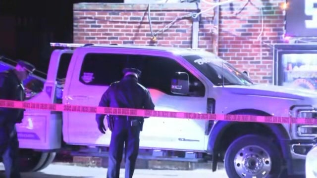 Police tape and officers are seen near a white tow truck 