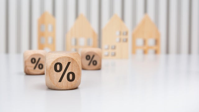 wooden cubes with percent signs in front of wooden houses 