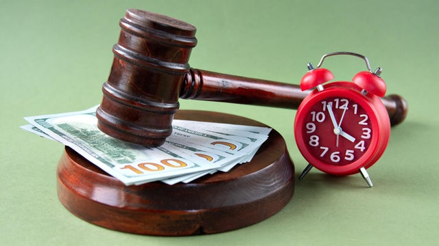 The judge's gavel lies on the counter against the background of banknotes and an alarm clock 