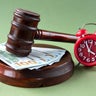 The judge's gavel lies on the counter against the background of banknotes and an alarm clock 