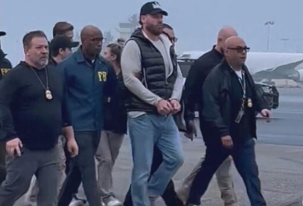 Ryan Wedding, center, is escorted by federal authorities after arriving at Ontario International Airport in Southern California, Jan. 23, 2026. 