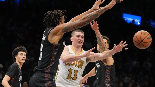 Boston Celtics' Payton Pritchard (11) passes away from Brooklyn Nets' Nic Claxton (33) and Michael Porter Jr. (17) during the second overtime of an NBA basketball game Friday, Jan. 23, 2026, in New York. 