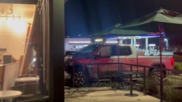 A truck with damage to its front-end partially inside a building 