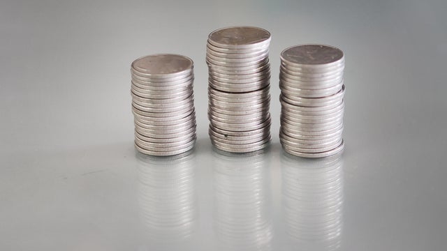 Many coins are stacked in rows orderly reflection on table mirror reflection on blurred background 