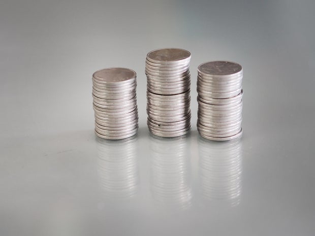 Many coins are stacked in rows orderly reflection on table mirror reflection on blurred background