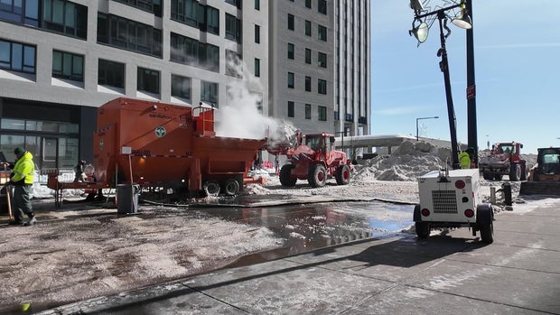 A front-loader drops snow into a snow-melter