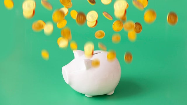 Financial freedom concepts still life -  gold coins flying on top of piggy bank. 