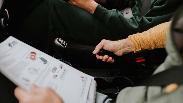 Close-up of a driving instructor showing his student how to use the hand brake 