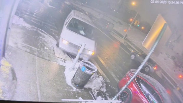 A white van mounts a curb onto a sidewalk 
