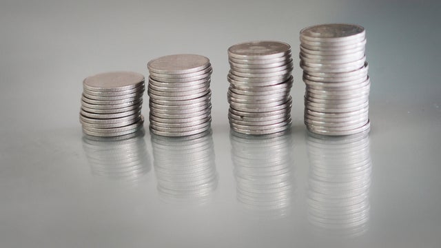 Many coins are stacked in rows orderly reflection on table mirror reflection on blurred background 