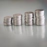Many coins are stacked in rows orderly reflection on table mirror reflection on blurred background 