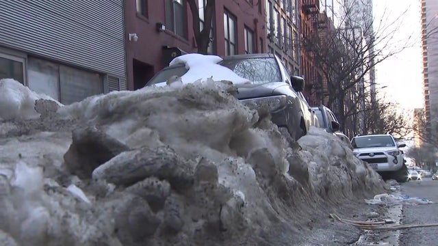 cars parked on street surrounded by snow 