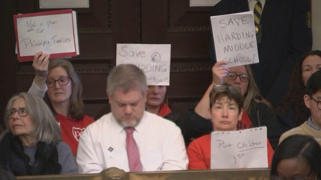 Community members hold up signs during a hearing about the school district proposal 