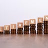 Retirement Word on Wooden Block with Stacked Coins on White Background 