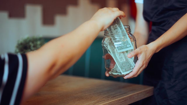 Customer Puts Money in the Tip Jar in a Restaurant 