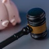 A broken pink piggy bank and a judge's gavel. 