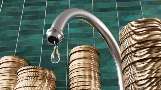 Water droplet dripping from a kitchen water tap surrounded by stacks of gold coins with green rectangular tiles as background. Illustration of the relationship between pipe leakage and money 