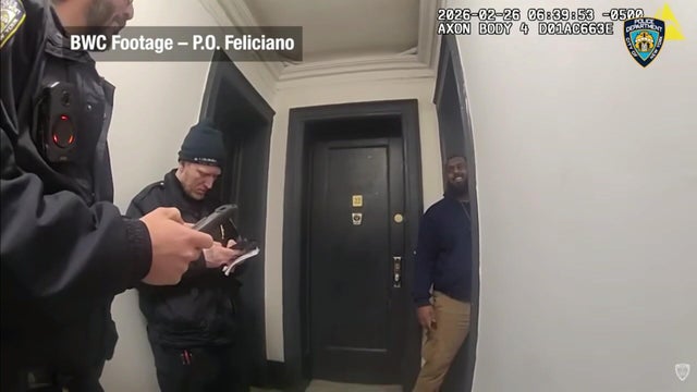 Two NYPD officers in a residential building hallway with an ICE agent. 