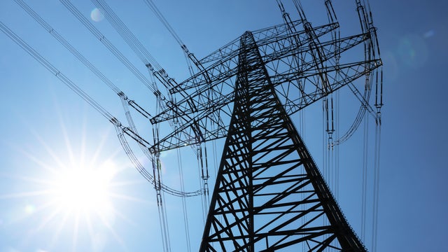 Tall large electricity pylon with bright sun 