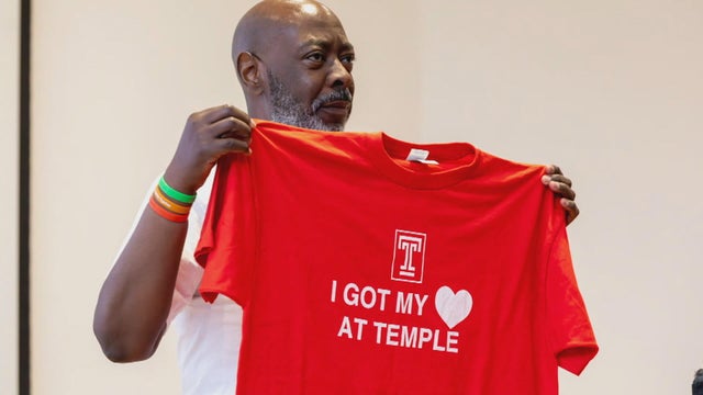 Earl Jones holds up a red t-shirt that says I got my heart at Temple 