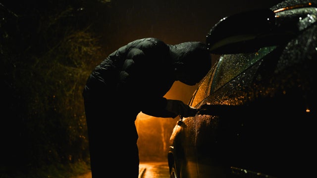 Man with hood trying to break into car. 