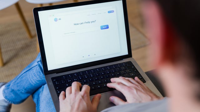 Person typing on laptop using AI chatbot assistant 