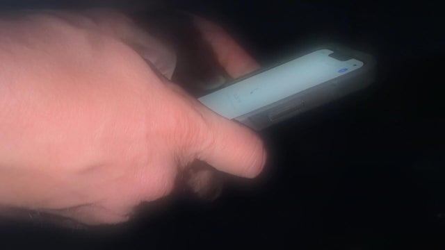 A hand types on a cellphone 