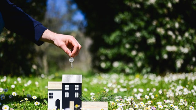 Real estate agent holding keys of new house in a field of daisies 